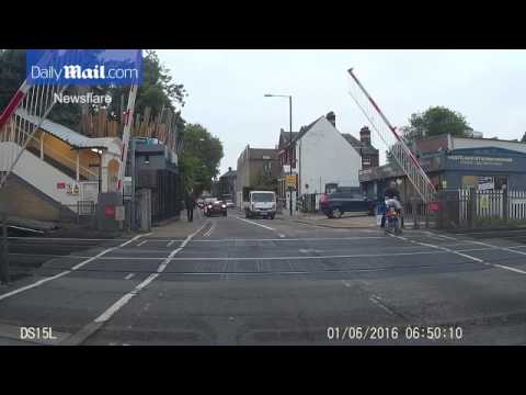 رجل يعرض حياة طفله للخطر بعبور مزلقان قطار