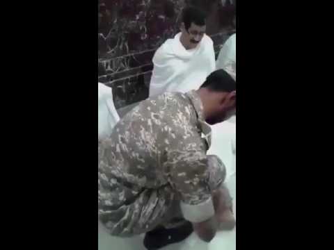 رجل أمن بالحرم المكي يدلك قدم معتمر أنهكه التعب
