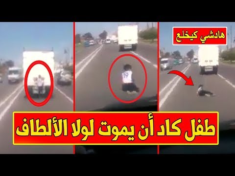 شاهدطفل مُعلق في باب سيارة يسقط أرضًا